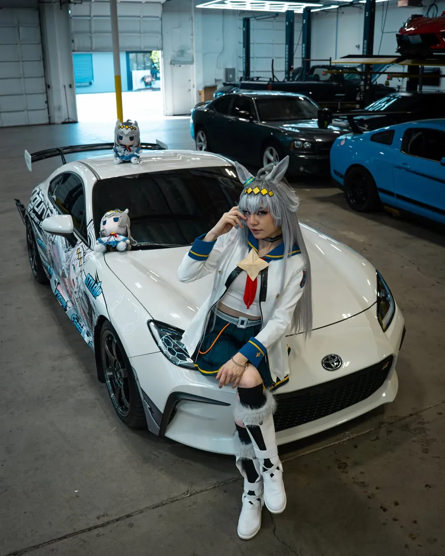 Oguri Cap cosplayer sitting on the Oguri Cap itasha Toyota GR86