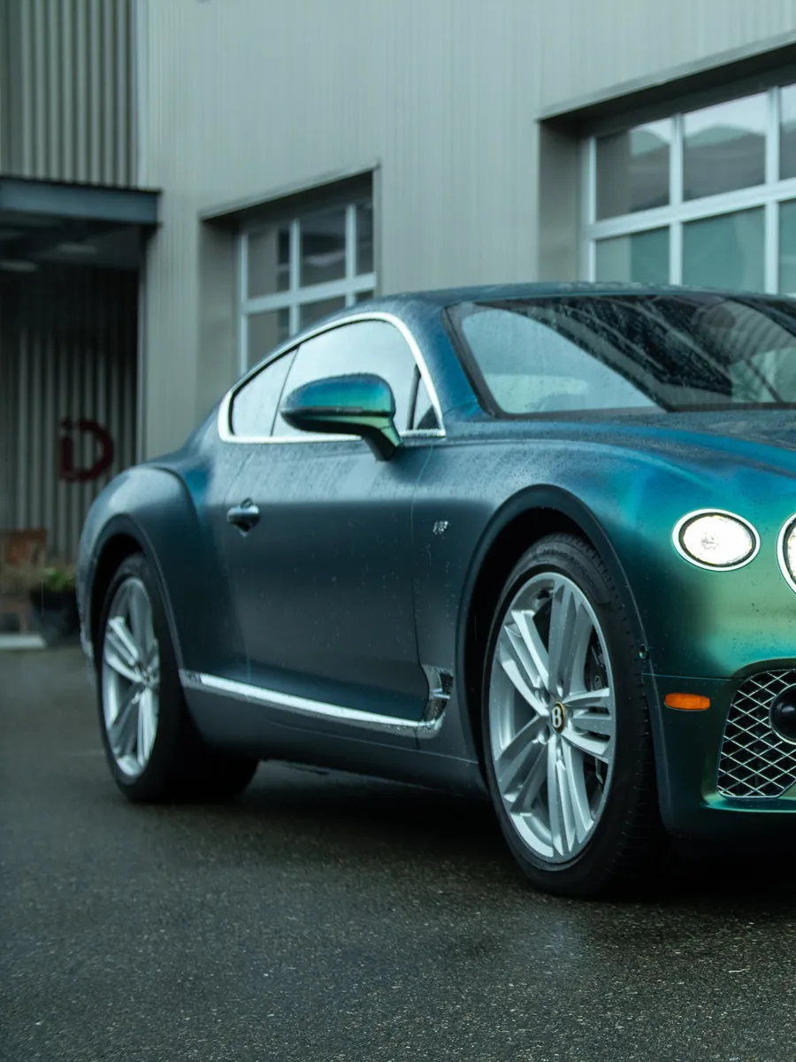 Bentley Continental GT in green color-shift PPF outside the EMWRAPS shop