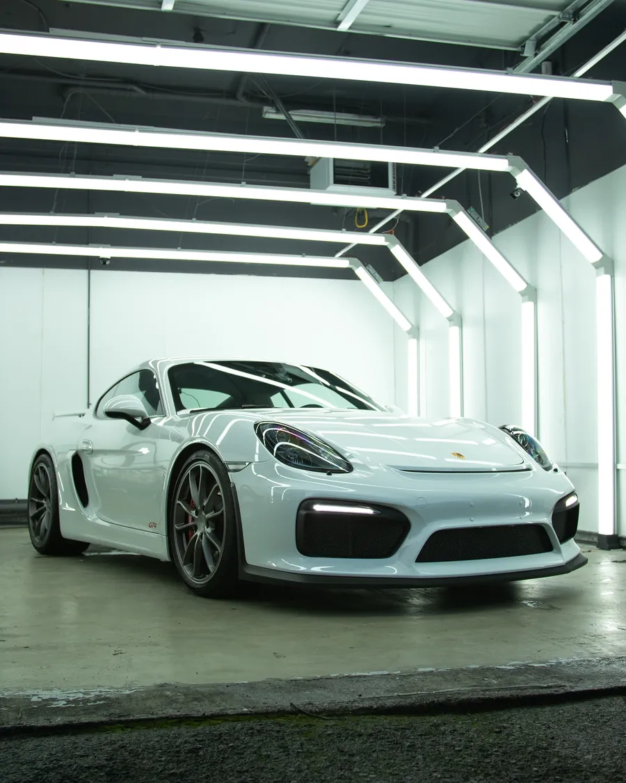 White Porsche Cayman GT4 with full body clear PPF in the EMWRAPS install bay