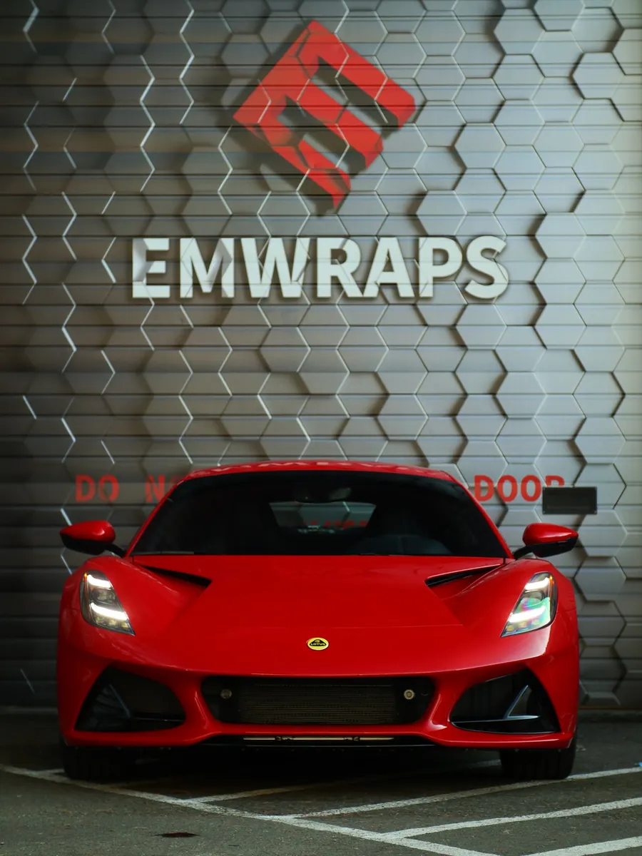 Red Lotus Emira with full gloss PPF in front of the EMWRAPS wall