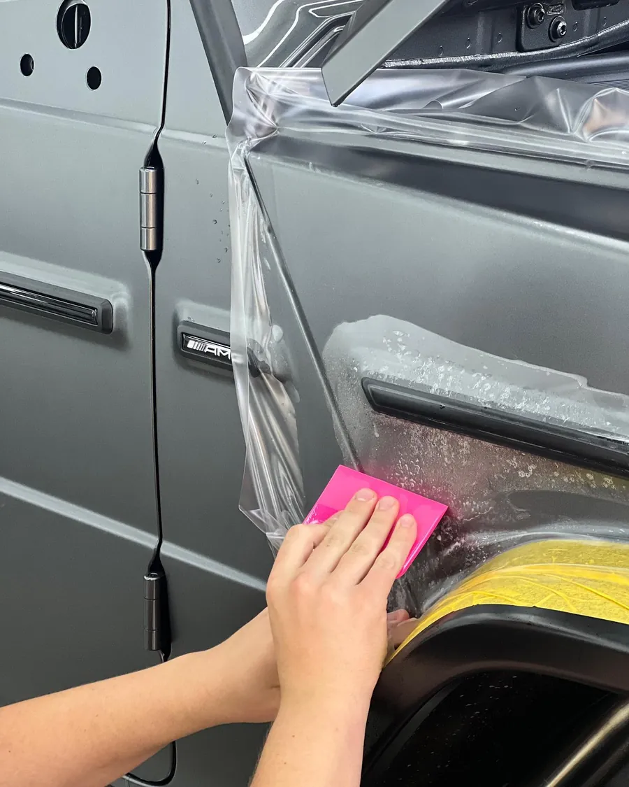 Installer squeegeeing stealth PPF onto the fender of a Mercedes-AMG G 63