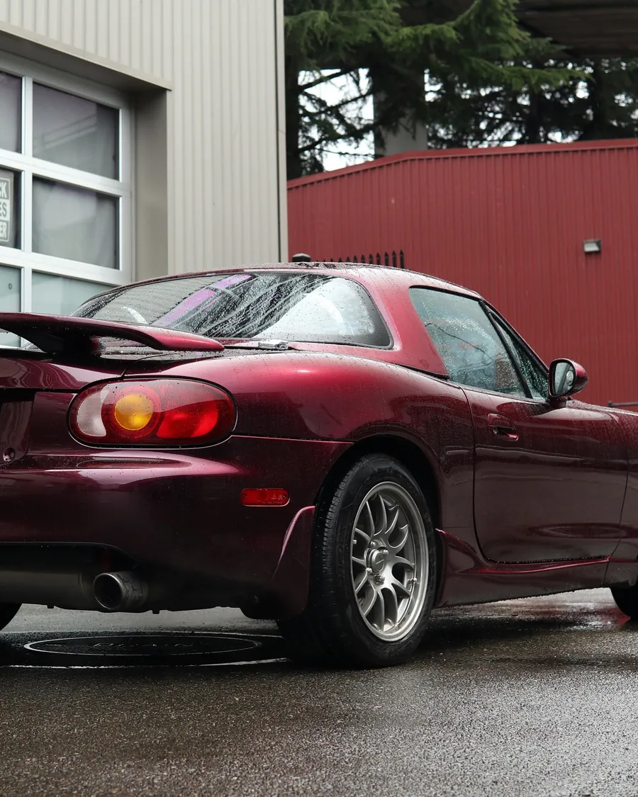 NB Mazda Miata in Black Rose color PPF, rear three-quarter view in the rain