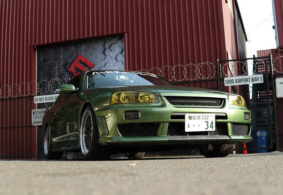 Nissan Skyline R34 four-door in Millennium Jade Green color PPF outside the EMWRAPS shop