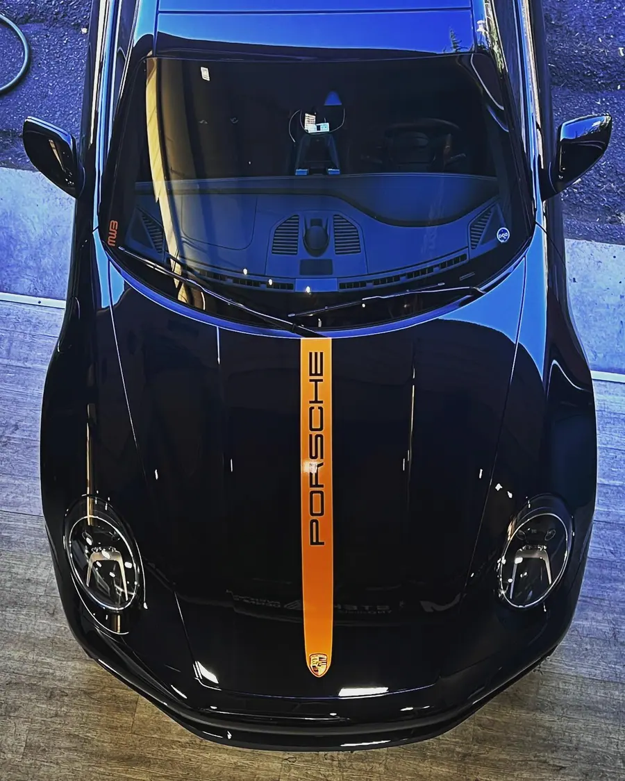 Black Porsche 911 with an orange Porsche stripe down the hood